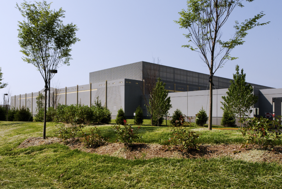 Exterior view of KDC Digital Realty Trust facility with landscaped surroundings and clear blue sky.
