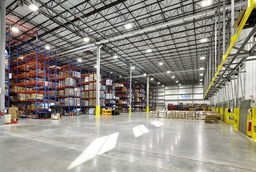 Spacious warehouse interior with stacked pallets, high ceiling, and bright lighting. Industrial storage and logistics concept.