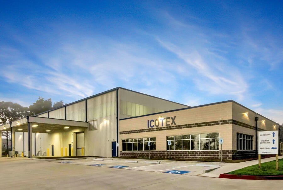 Modern ICOTEX building under a clear blue sky with accessible parking spaces in front.