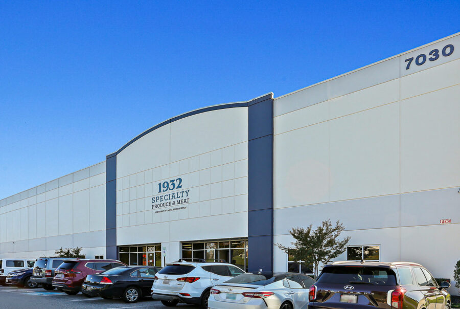 Saval Foods Retrofit: Exterior of a large warehouse with parked cars, labeled 1932 Specialty Produce & Meat.