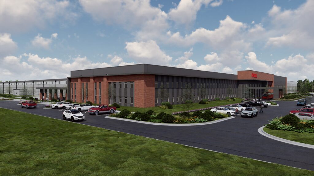 Modern brick building with parking lot, green landscape, and cloudy sky; showcasing corporate office architecture.