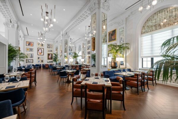 Grand dining room in a converted historic hall with original columns, plasterwork and a salon-style gallery wall