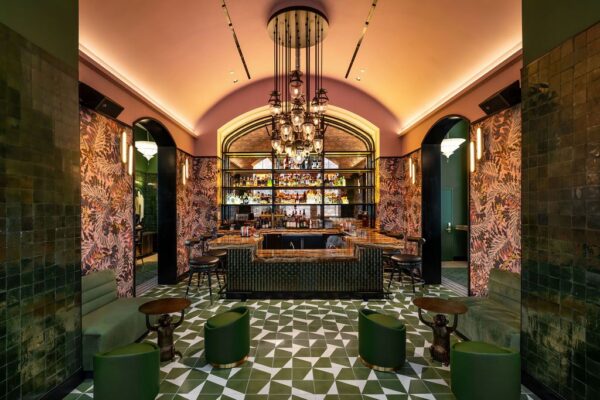 Vaulted basement bar with botanical murals, green tilework and a patterned tile floor
