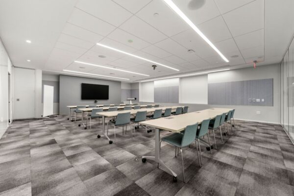 Training room with mobile tables, teal task chairs and a wall-mounted display