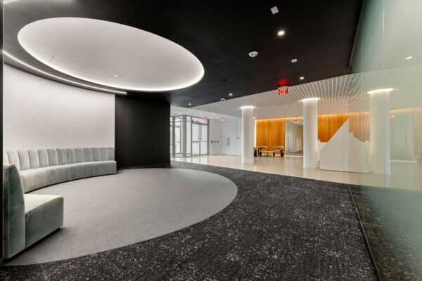 Office lobby with a curved banquette under an illuminated oval ceiling and a terrazzo floor