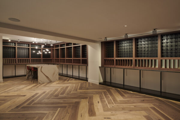 Private wine room with floor-to-ceiling storage racks, a stone tasting island and herringbone wood floors