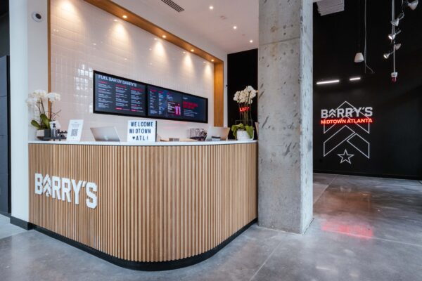 Barry's Midtown Atlanta front desk in fluted wood beneath backlit menu screens