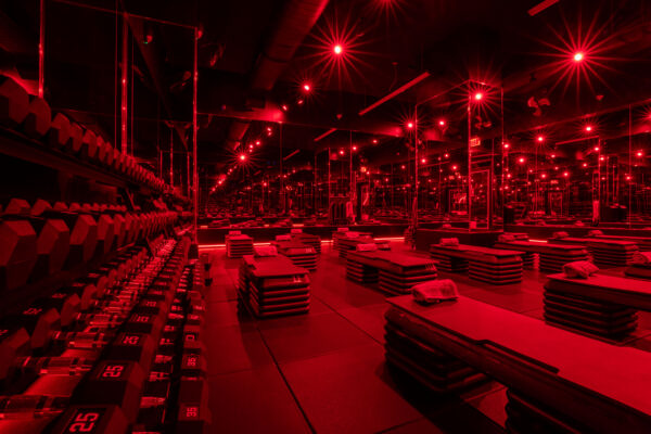 Barry's studio floor under red lighting, with dumbbell racks and mirrored walls